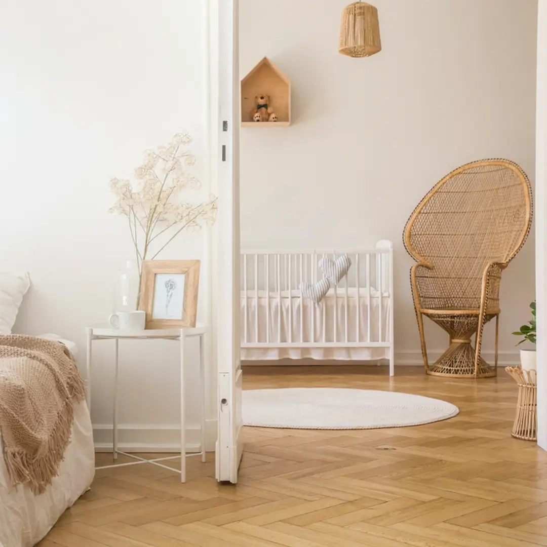 Fischgraet Parkett Schlafzimmer boho stil mit Sicht auf ein kleines Kinderzimmerbett und ein gemütlicher Rattanstuhl