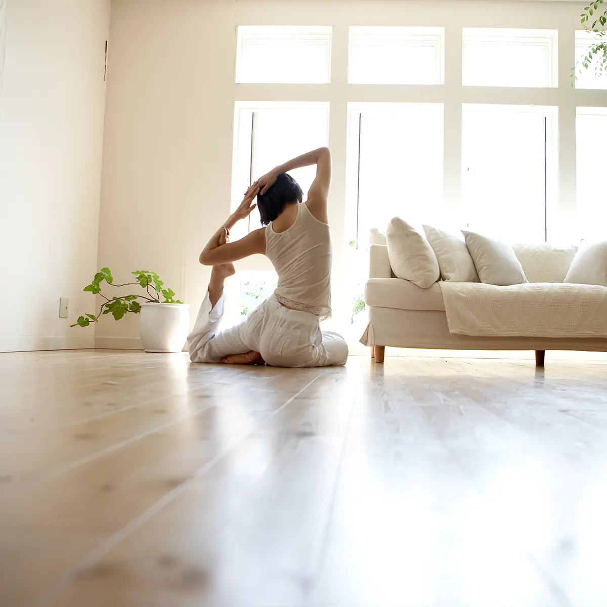 Frau sitzend in Yoga Haltung im Wohnzimmer